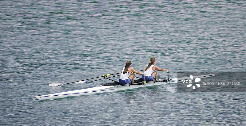 下午晚些时候，两名女运动员划船横渡湖泊图片素材