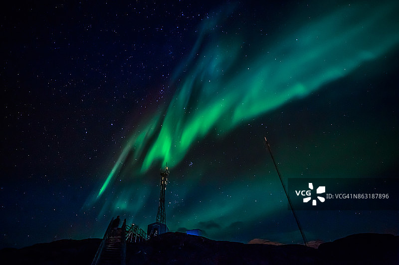 绿波北极光与闪耀的星星越过山脉和无线电塔，格陵兰岛努克图片素材