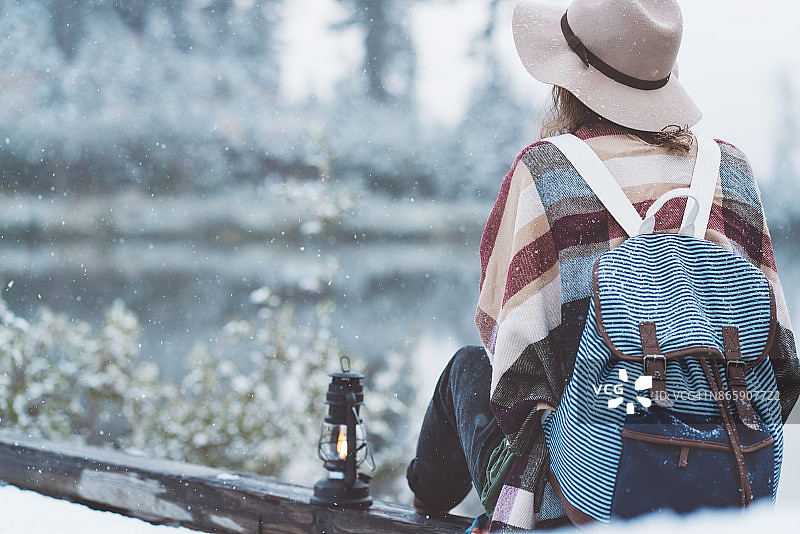 女旅人拿着煤油灯在雪湖边欣赏风景图片素材