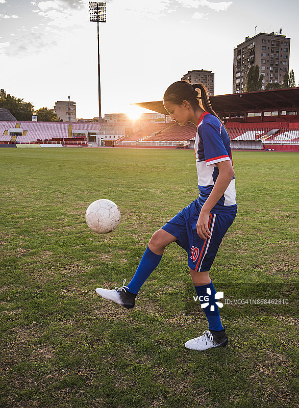 坚定的女足运动员在场上用球练习。图片素材