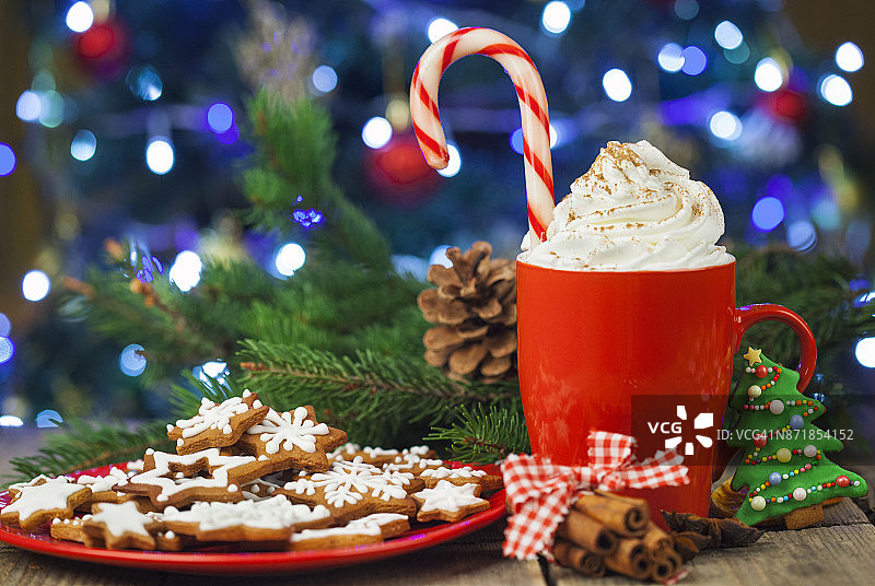圣诞卡布奇诺和姜饼饼干在圣诞树前，在乡村木桌上图片素材