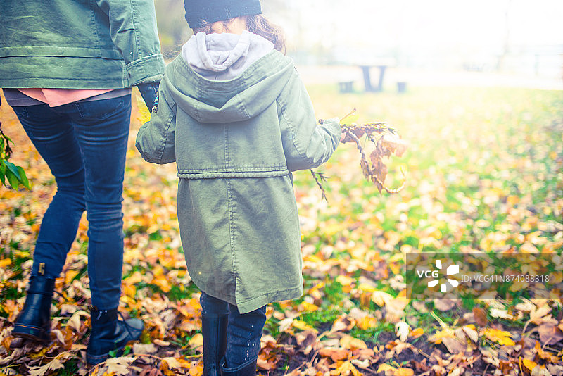 秋天的公园里，妈妈和女儿手牵着手走着图片素材