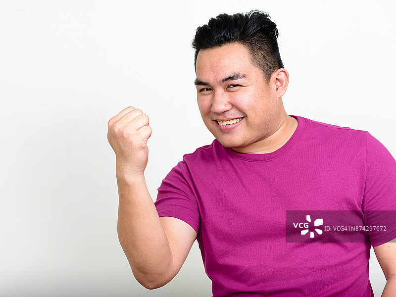 年轻英俊的亚洲男子穿着紫色衬衫对抗白色的背景图片素材