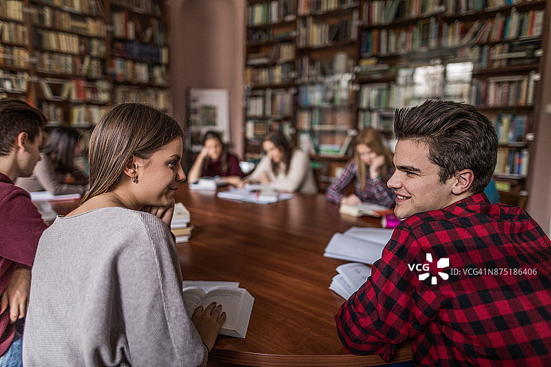 微笑的学生在图书馆互相交谈。图片素材
