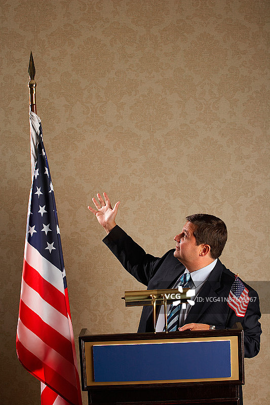 政治家在讲台上向美国国旗做手势图片素材