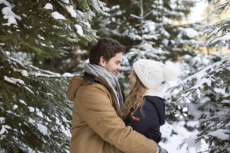 幸福的年轻夫妇面对面在白雪覆盖的冬季森林图片素材