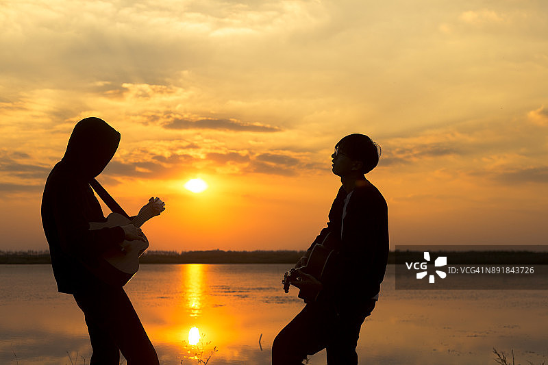 夕阳下弹奏吉他的男人的剪影图片素材