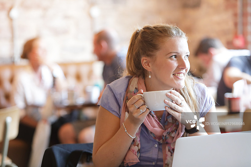 一个女人在咖啡店里用笔记本电脑放松图片素材