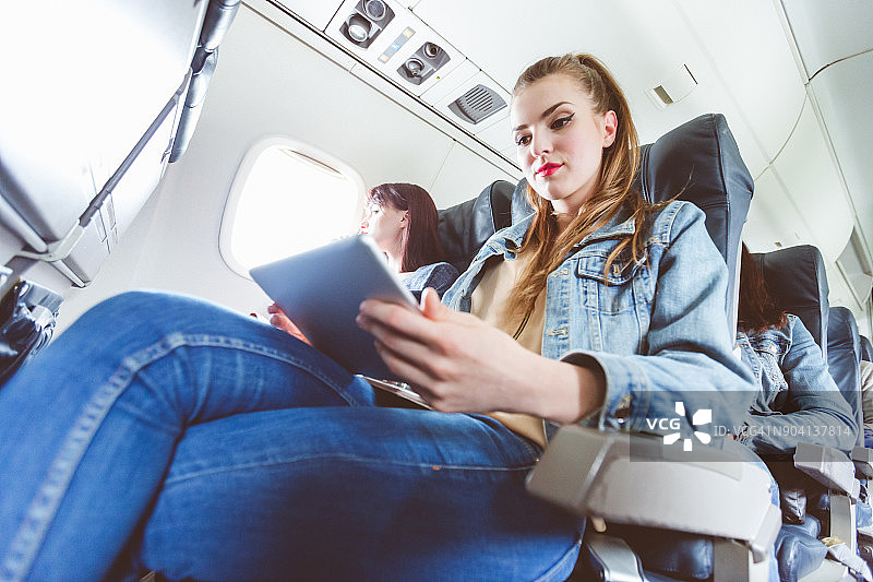 女性乘客在飞行中使用平板电脑图片素材