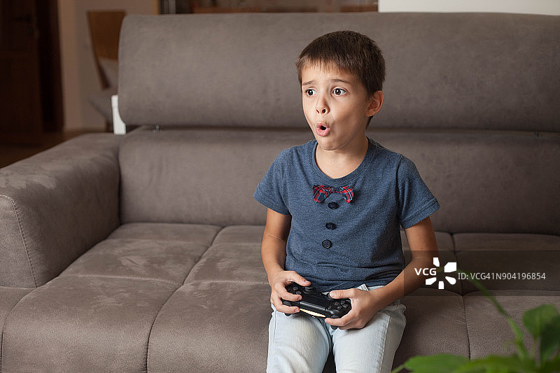 男孩坐在沙发上玩电子游戏图片素材