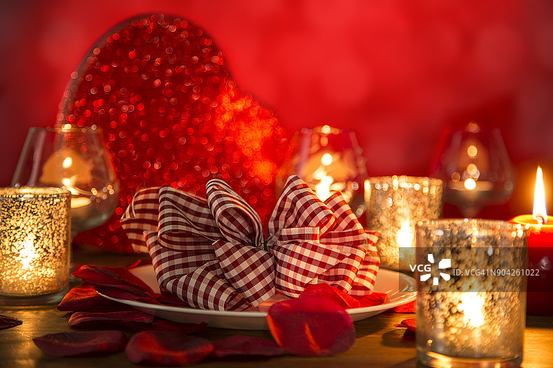 情人节的浪漫烛光晚餐与心和玫瑰花瓣。图片素材