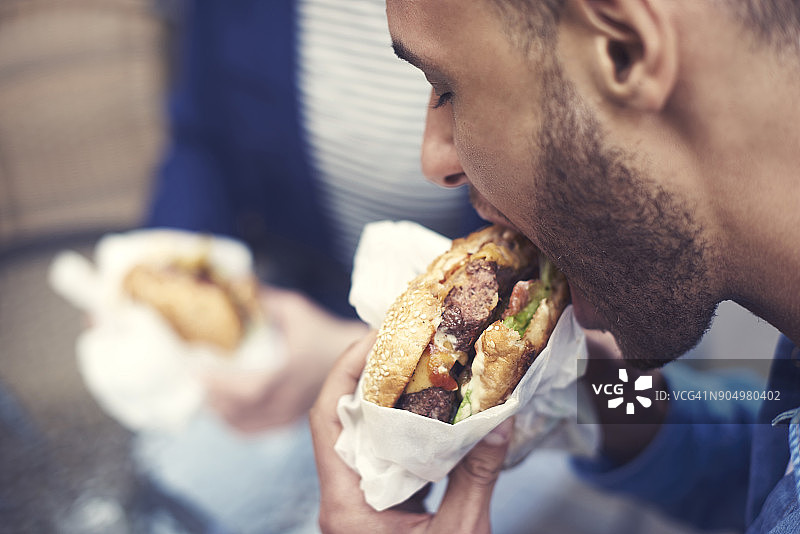 男人吃起司汉堡的特写。克拉科夫,波兰图片素材