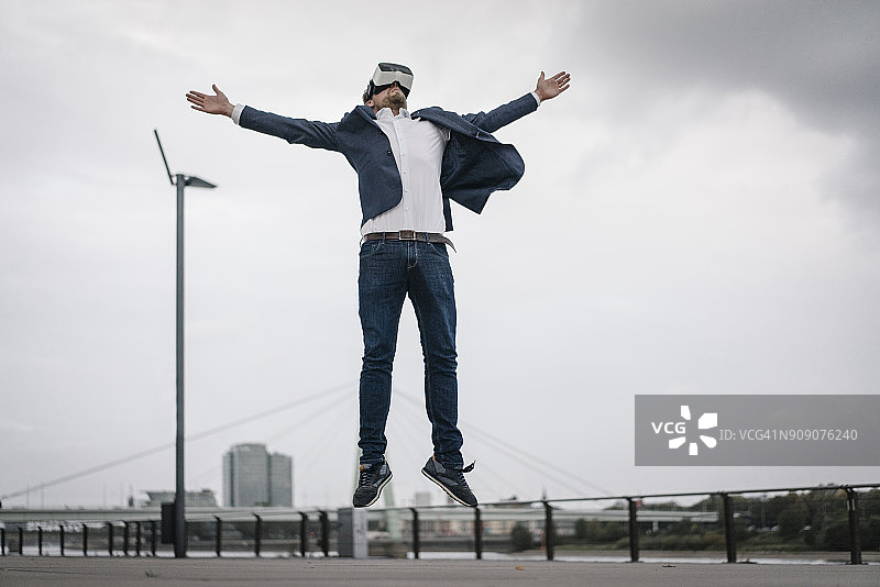 商人戴着VR眼镜在城市中跳跃图片素材