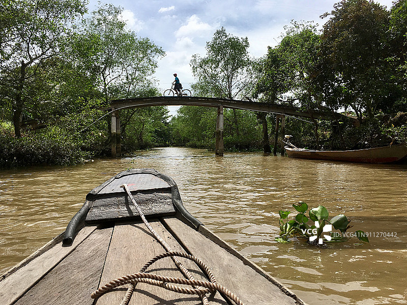越南湄公河三角洲运河，从船POV上骑自行车的人图片素材