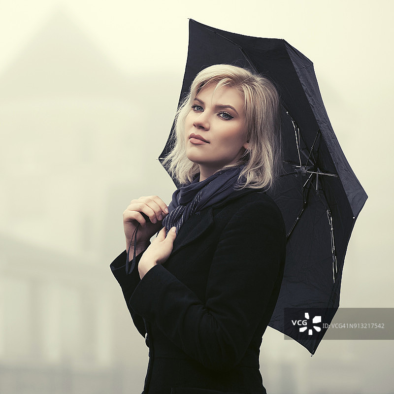 年轻时尚的女人撑着伞在雾中行走图片素材