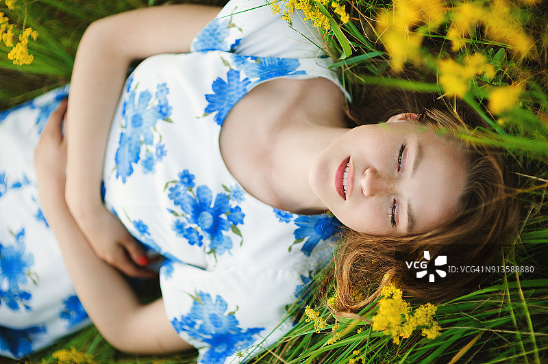 美丽的少女微笑着躺在田野的草地上图片素材