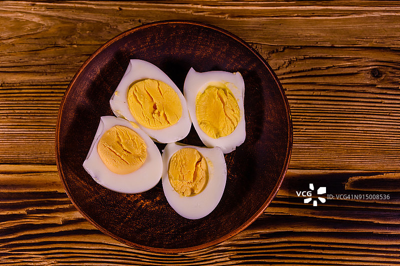 陶瓷盘子和去皮煮鸡蛋放在木桌上。俯视图图片素材
