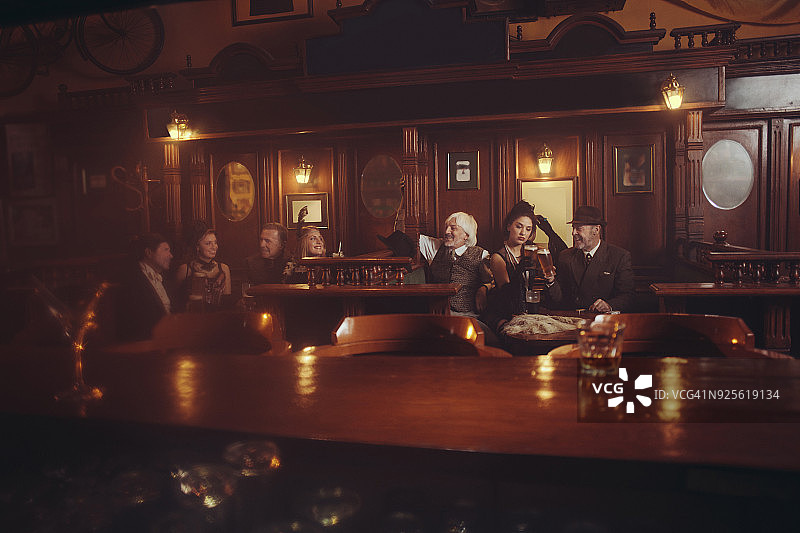 庆祝复古酒吧老式的一群老男人和年轻女人喝啤酒聚会图片素材