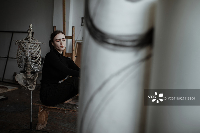 一个女人在画室里和骷髅坐在一起图片素材