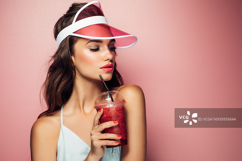 时尚漂亮酷的女孩从粉红色的背景杯饮料图片素材