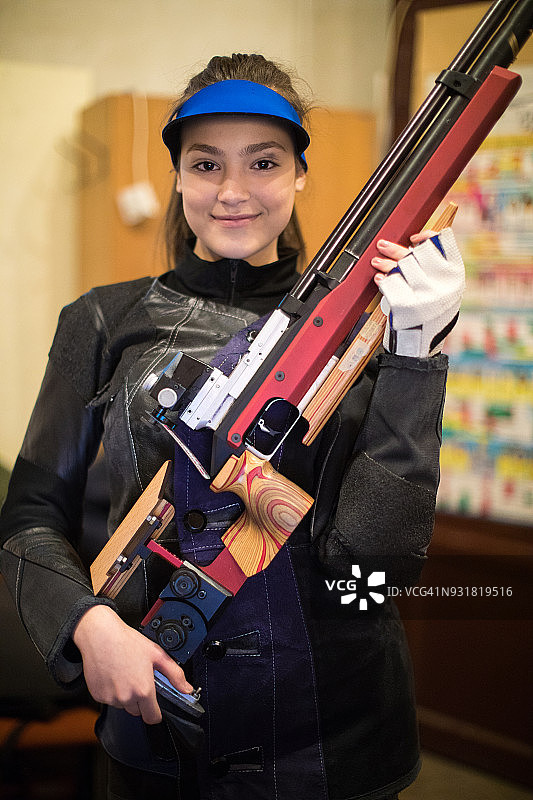 一个微笑的年轻女子的肖像拿着她的运动步枪图片素材