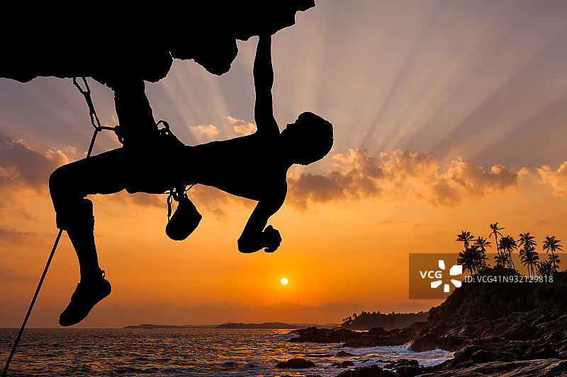 剪影的攀岩者攀登一个悬崖与日落图片素材