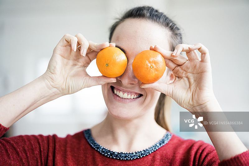 笑着用橘子遮住眼睛的女人图片素材