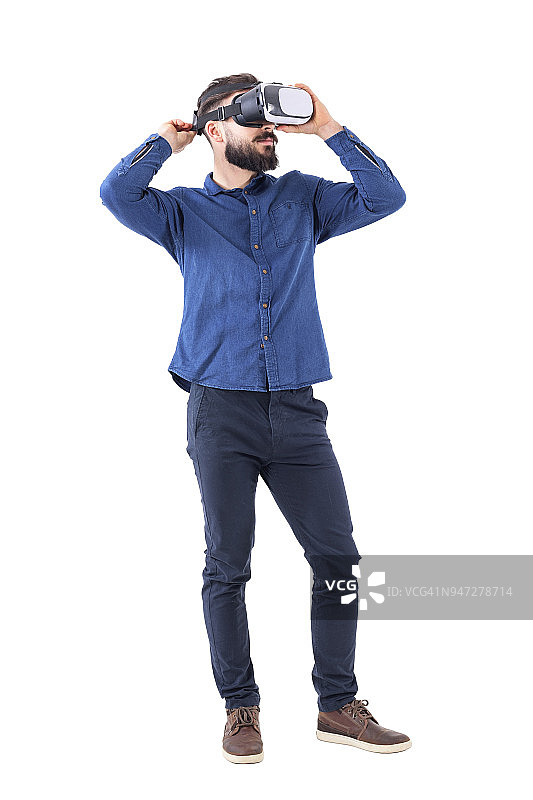 年轻的大胡子男子试着戴上虚拟现实眼镜。图片素材