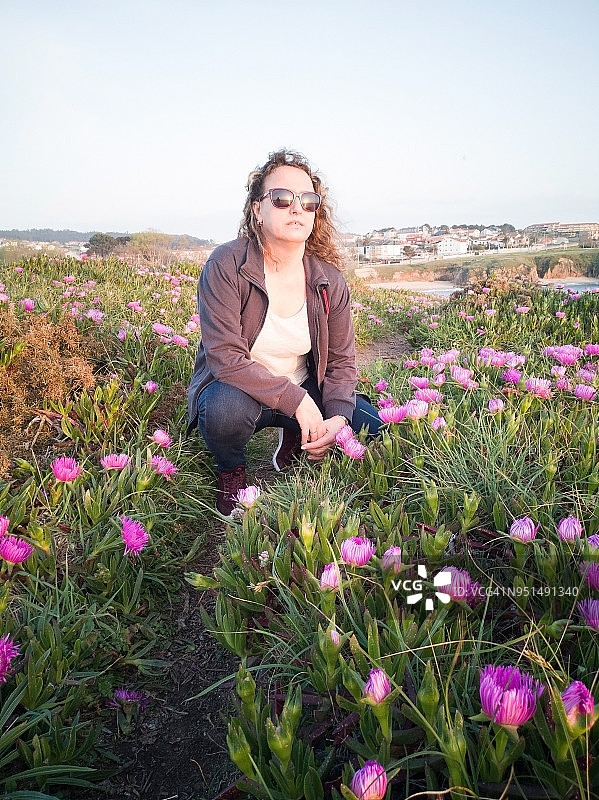 一个女人坐在长满花的草地上图片素材