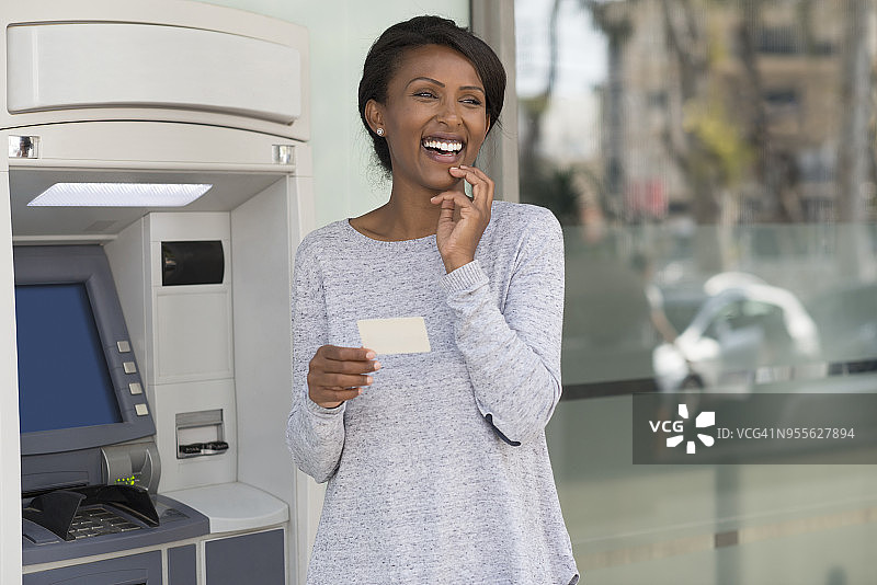 快乐的银行持卡人女人满意她的信用卡/借记卡，银行账户和ATM服务。图片素材