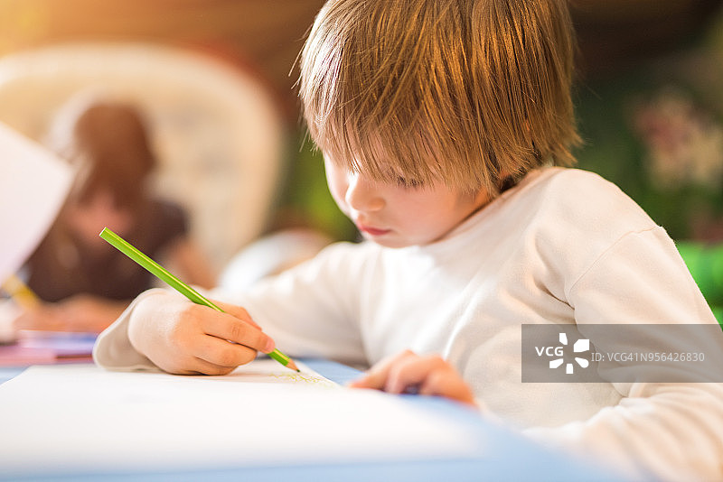 快乐的小男孩喜欢在幼儿园里画画。图片素材