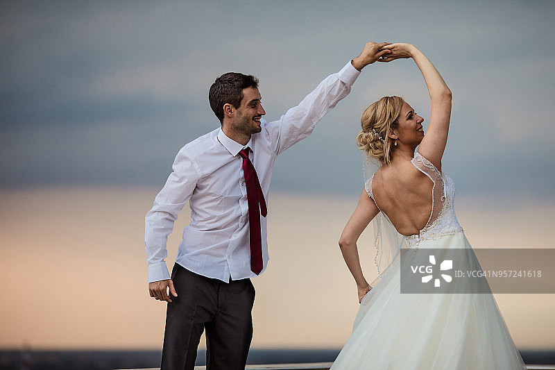 幸福的新娘和新郎享受着对着天空的舞蹈。图片素材