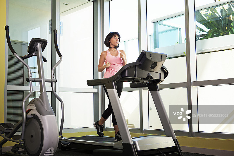 全长女人在跑步机上锻炼在健身房图片素材