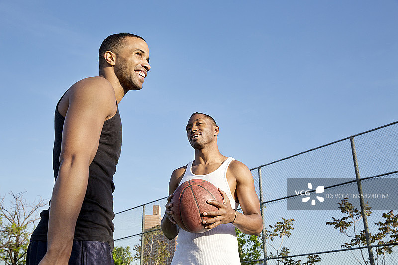 低角度的快乐篮球运动员站在球场上对抗晴朗的天空图片素材