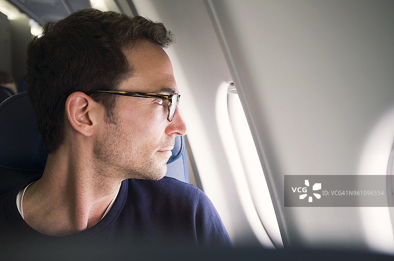 一个男人透过飞机窗户向外看的特写图片素材
