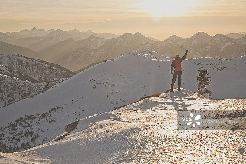 在日落时分，用冰斧在白雪皑皑的山上徒步旅行图片素材