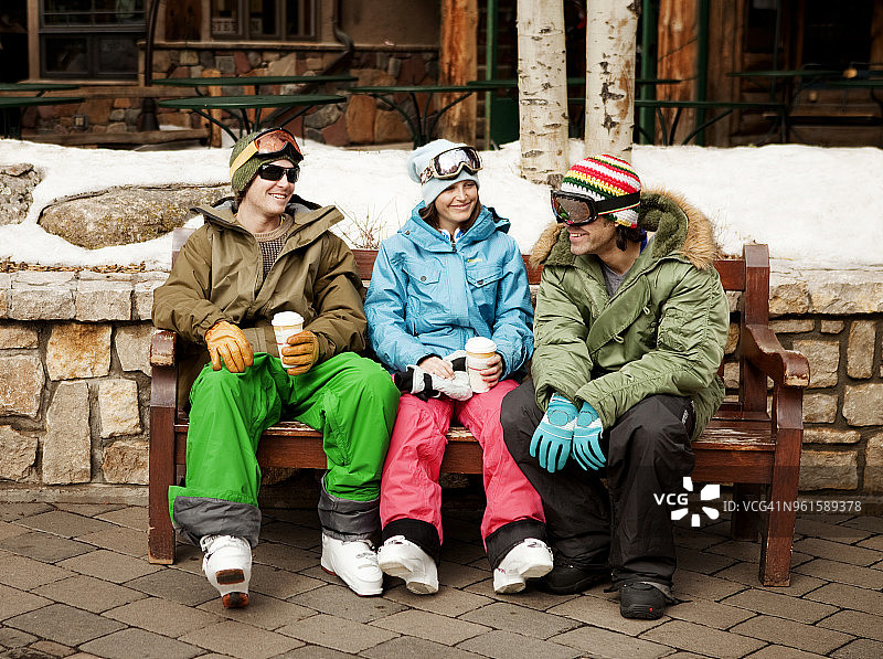 快乐的滑雪者坐在滑雪场的长椅上图片素材
