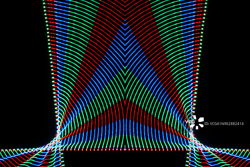 近距离的抽象图案交错的彩色光束的颜色红色，绿色和蓝色在一个黑色的背景。图片素材