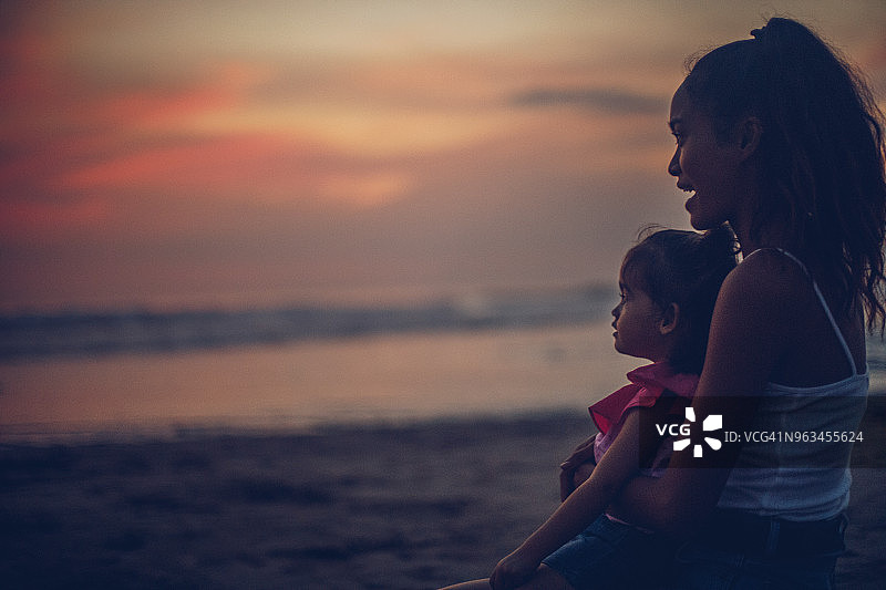 母亲和小女儿在海滩上欣赏日落图片素材