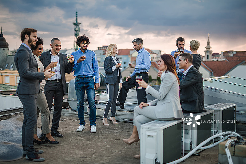 一大群快乐的商业同事在屋顶聚会上聊天。图片素材