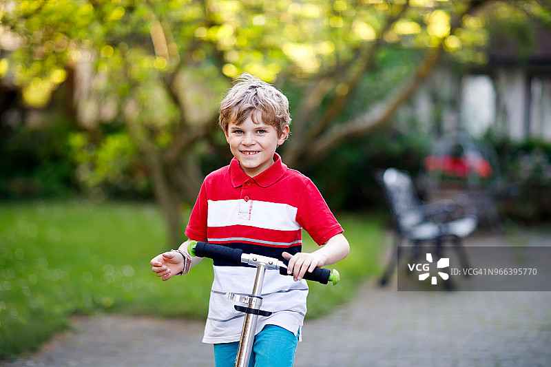 可爱的小男孩骑着滑板车去上小学。儿童未戴安全帽，图片素材