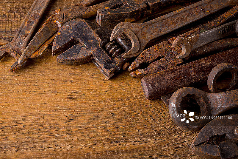 木制背景上的一套肮脏的、旧的、生锈的工具。锁匠及金工车间设备图片素材
