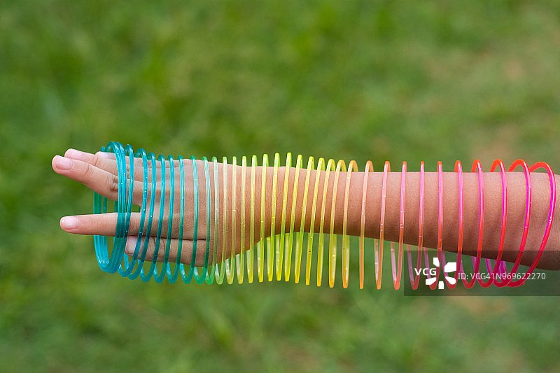 女孩玩彩虹色的电线螺旋玩具在白色的背景。图片素材