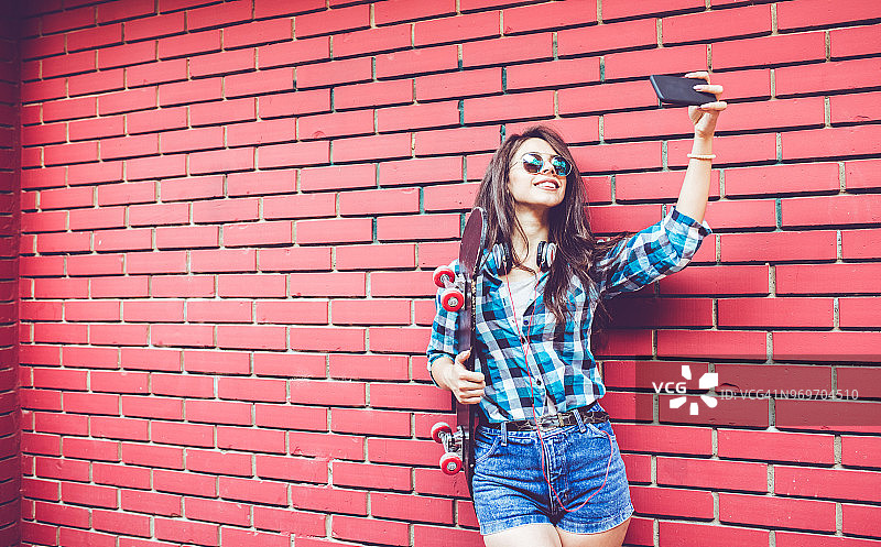 女孩站在带滑板的红砖墙旁图片素材