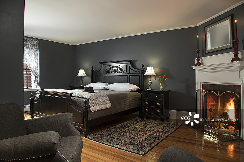 现代卧室内饰有壁炉，木地板，油漆墙壁和男性灰色和黑色配色方案图片素材