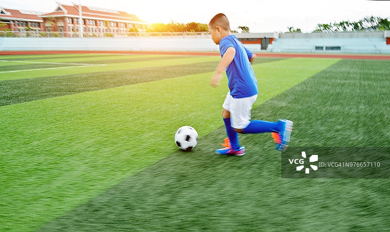 小男孩在操场上踢足球图片素材