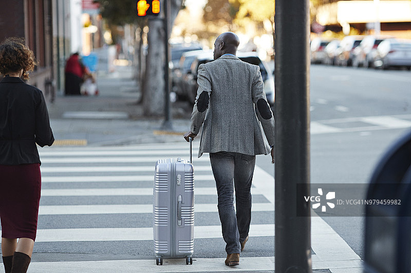 在人行横道上提着行李箱的商人图片素材
