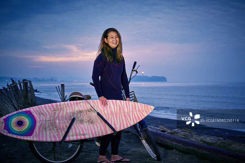 妈妈的年长冲浪者携带板在日出前在日本的Enoshima。图片素材