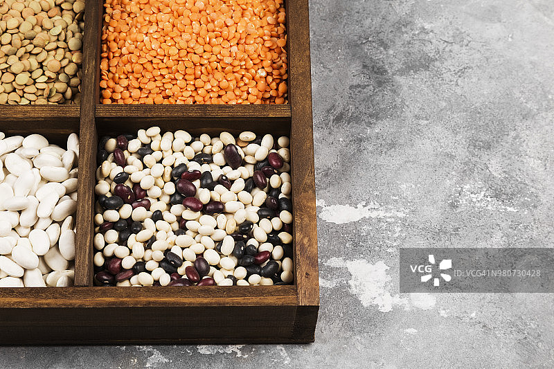 各种各样的豆子(红扁豆，绿扁豆，鹰嘴豆，豌豆，红豆，白豆，混合豆，绿豆)在灰色的背景。副本的空间。食品的背景图片素材