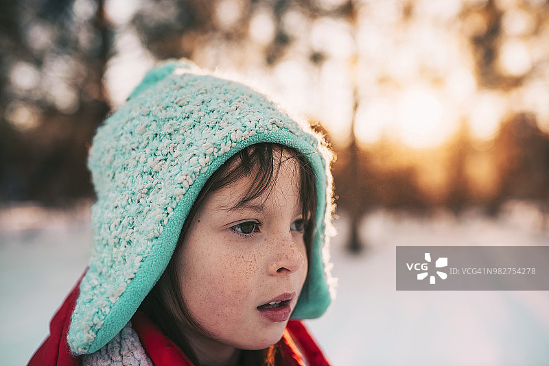 一个微笑的女孩站在雪地里的肖像图片素材
